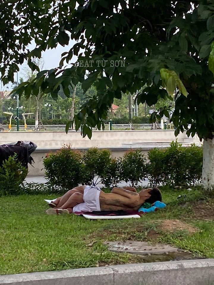 Hình ảnh cặp đôi ăn mặc mát mẻ, vô tư nằm ôm ấp nhau ngoài bãi cỏ giữa cái nắng nóng 40 độ khiến nhiều người khó chịu - Ảnh 1.