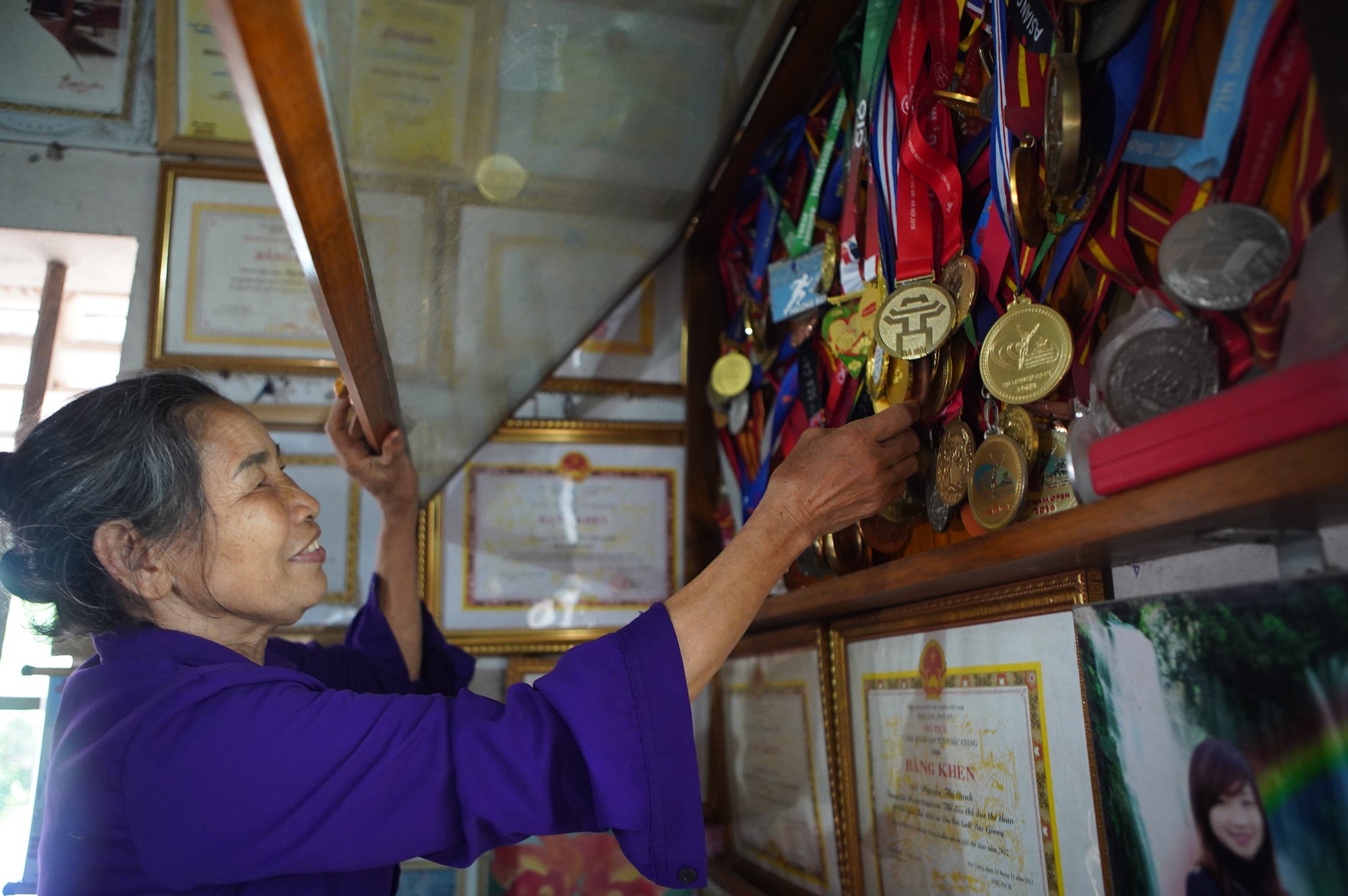 Người mẹ đang sắp xếp lại các bộ huy chương vàng của con gái