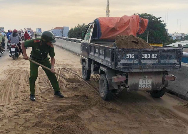 Cảnh sát giao thông cùng người dân dọn cát rơi trên đường ở Sài Gòn - Ảnh 2.