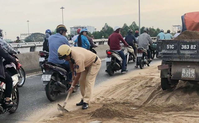 Cảnh sát giao thông cùng người dân dọn cát rơi trên đường ở Sài Gòn - Ảnh 1.