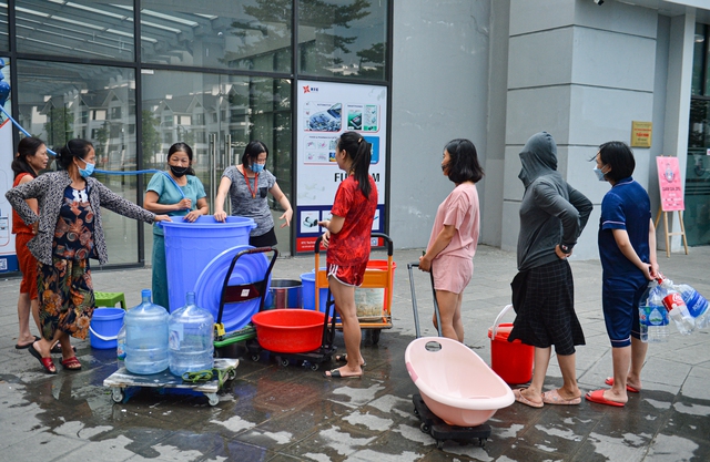 Ảnh: Hàng trăm người dân ở chung cư Hà nội đội mưa, xếp hàng chờ lấy nước sạch - Ảnh 2.