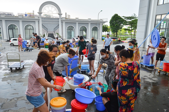 Ảnh: Hàng trăm người dân ở chung cư Hà nội đội mưa, xếp hàng chờ lấy nước sạch - Ảnh 1.