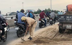 Cảnh sát giao thông cùng người dân dọn cát rơi trên đường ở Sài Gòn