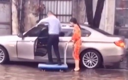 Người đàn ông ăn mặc lịch sự đứng trên xe đẩy để một phụ nữ (nghi là vợ) đưa lên ô tô cho khỏi ướt giày khiến dân mạng tranh cãi kịch liệt
